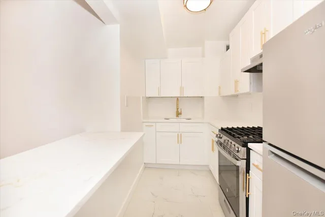 a kitchen with granite countertop a sink stove and white cabinets