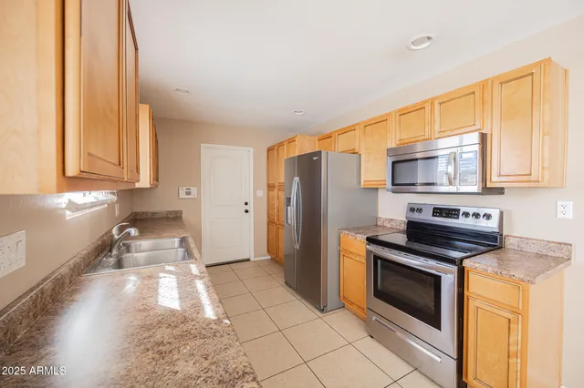 a kitchen with granite countertop a stove a sink and a refrigerator