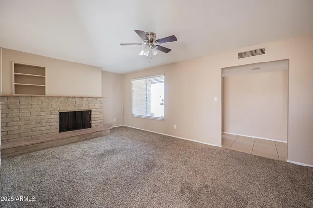 a view of empty room with a ceiling fan and fireplace