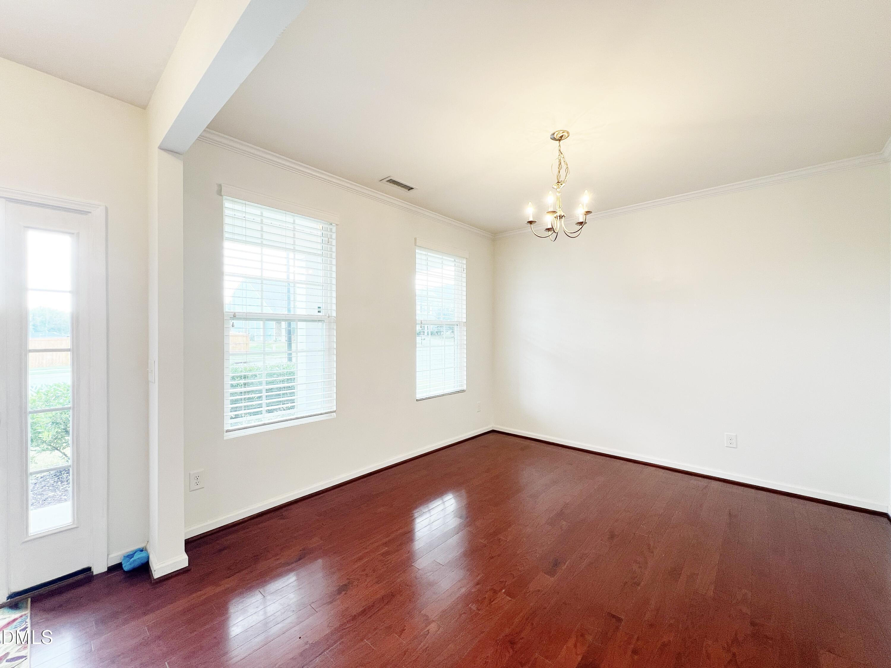 1495 Willowcrest Road Durham, NC 27703 - Photo 7 of 35 an empty room with wooden floor chandelier fan and windows