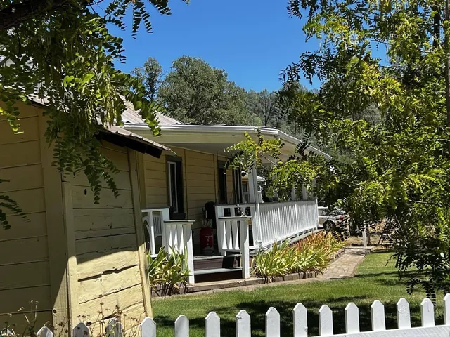 a view of a wooden house with large trees