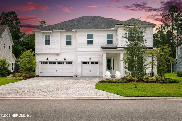 a view of a white house with a yard and large tree