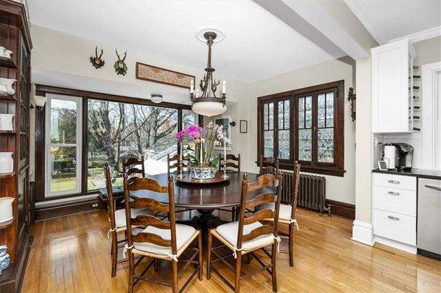 a dining room with wooden floor a chandelier a wooden table and chairs