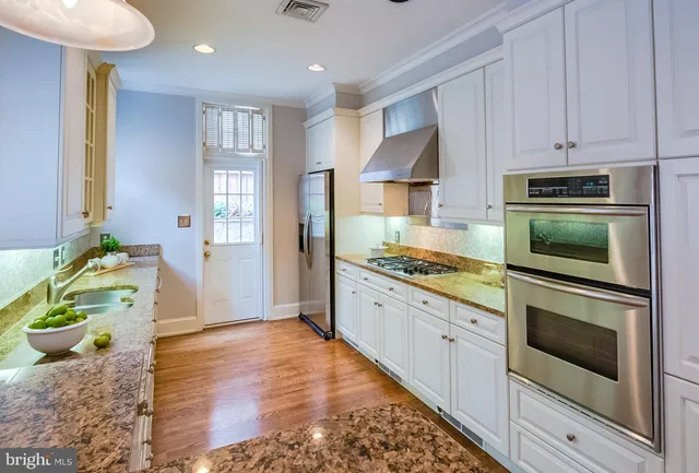 a kitchen with kitchen island white cabinets and stainless steel appliances