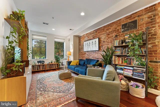 a living room with stainless steel appliances kitchen island granite countertop furniture a rug kitchen view and a chandelier