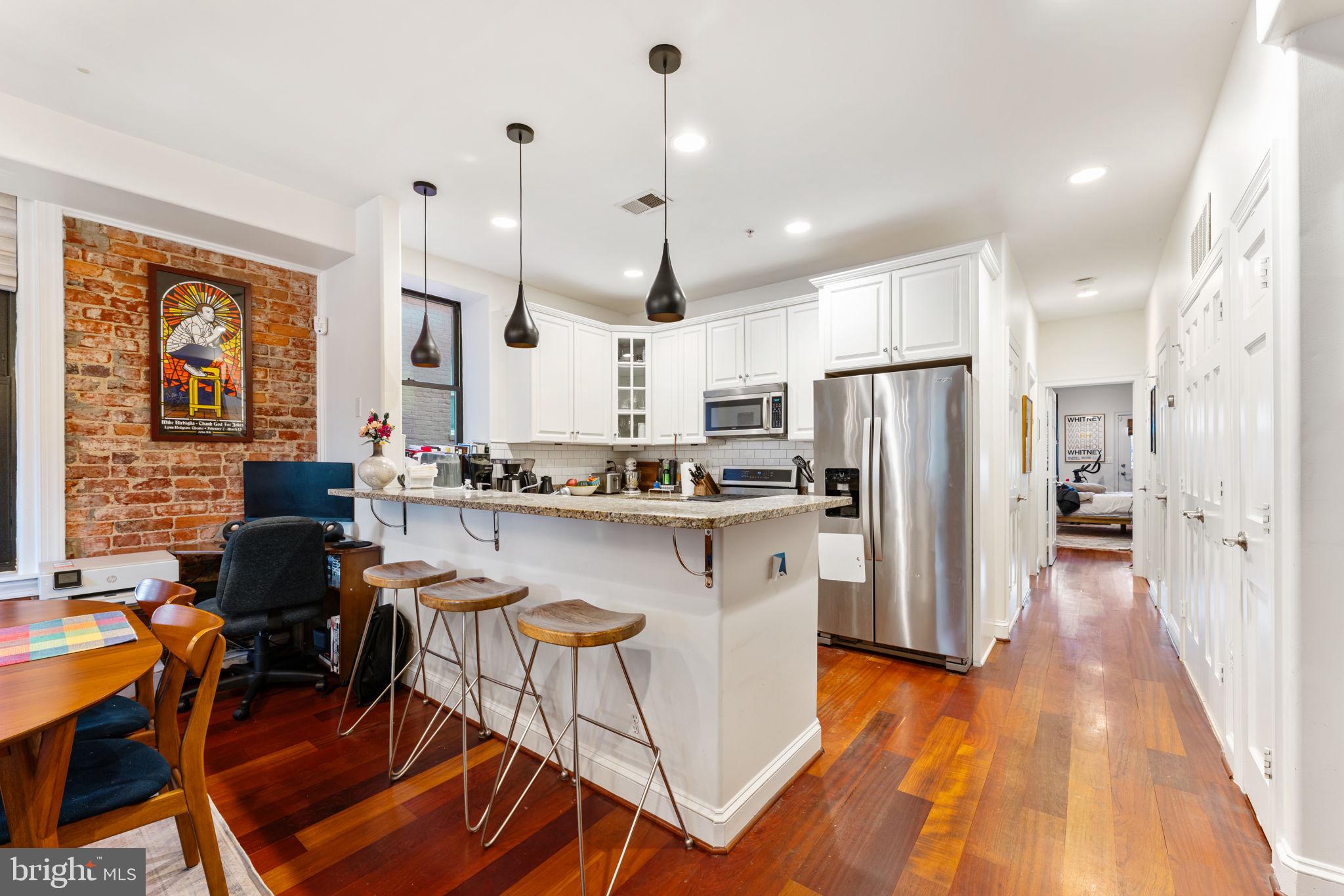 1105 Park Road Northwest, Unit 3 Washington, DC 20010 - Photo 6 of 20 a kitchen with stainless steel appliances a refrigerator a stove a sink dishwasher with a dining table and chairs with wooden floor
