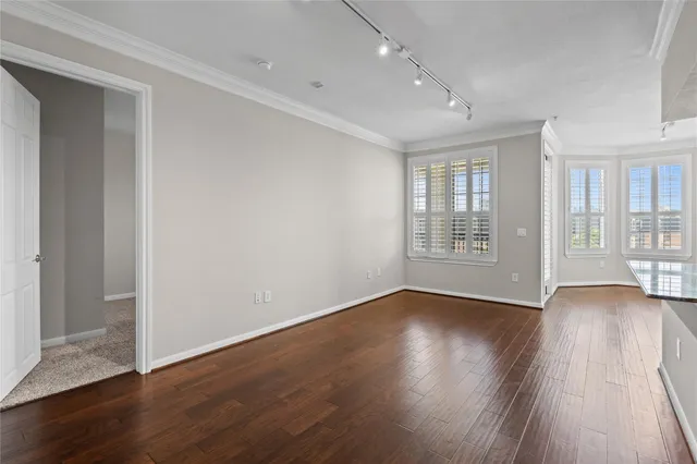 a view of an empty room with wooden floor and window