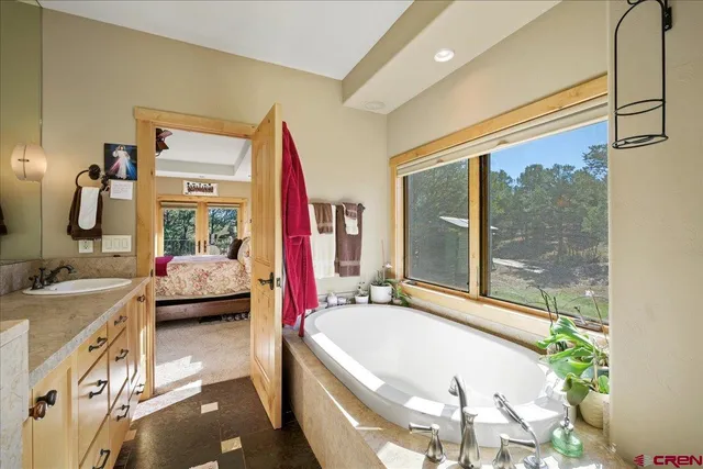 a en suite spacious bathroom with a granite countertop tub and a large mirror