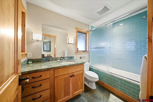 a bathroom with a granite countertop sink toilet mirror and bathtub