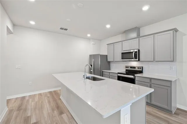 a kitchen with stainless steel appliances a sink a stove a microwave a center island and cabinets