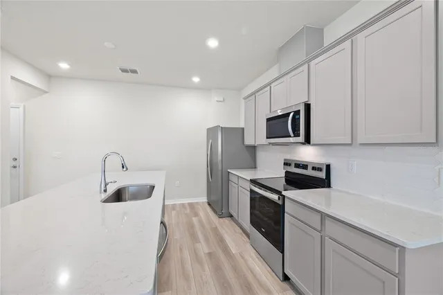 a kitchen with stainless steel appliances granite countertop a sink stove microwave and refrigerator