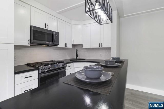 455 Fairview Avenue, Unit 5 Fairview, NJ 07022 - Photo 3 of 10 a kitchen with stainless steel appliances a stove a microwave a sink and cabinets