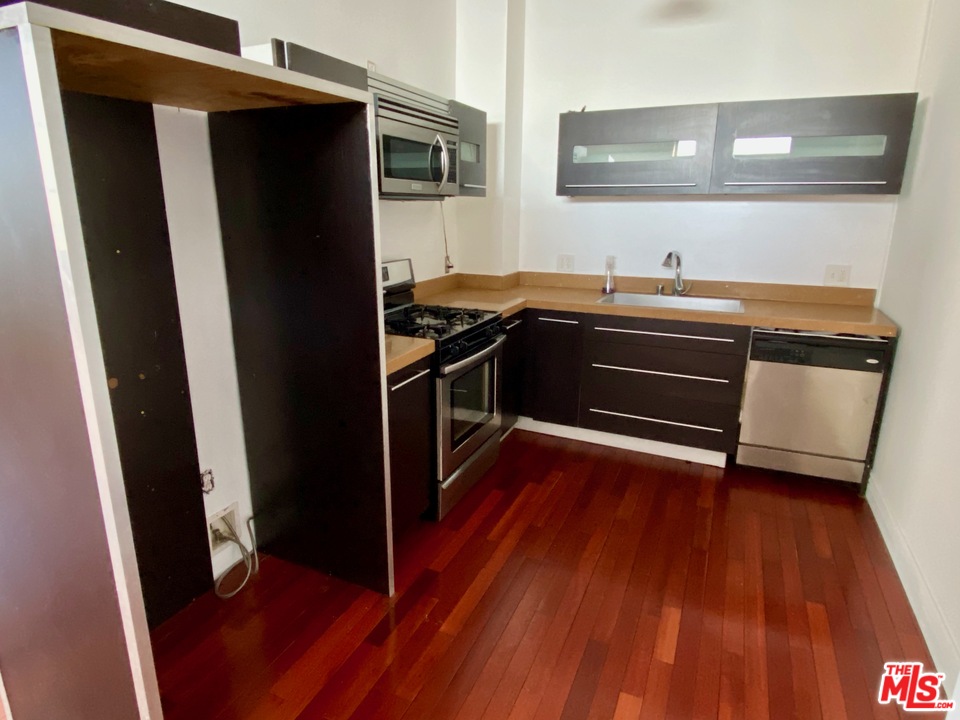 652 Mateo Street, Unit 202 Los Angeles, CA 90021 - Photo 5 of 9 a kitchen with granite countertop a refrigerator and a sink