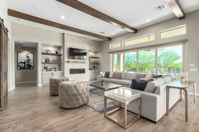a living room with couches and a flat screen tv with kitchen view