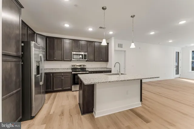 a kitchen with stainless steel appliances granite countertop a sink a stove and a refrigerator