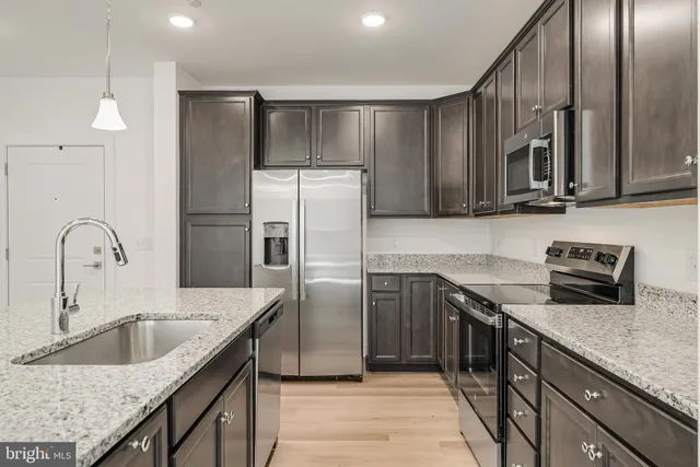 a kitchen with stainless steel appliances granite countertop a kitchen island a stove and a sink