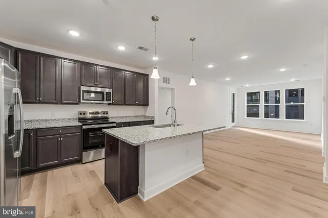 a kitchen with stainless steel appliances granite countertop a sink a stove and a refrigerator
