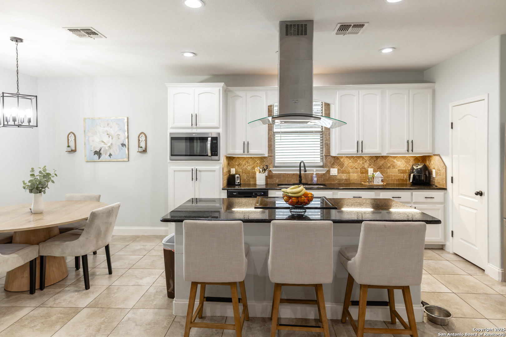 1038 Avenue H Poteet, TX 78065 - Photo 4 of 16 a kitchen with stainless steel appliances granite countertop a dining table chairs sink and cabinets