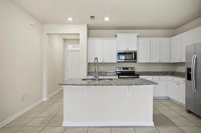 a kitchen with stainless steel appliances granite countertop a stove a sink and a microwave