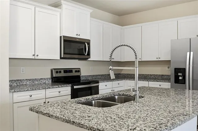 a kitchen with granite countertop a sink stainless steel appliances and cabinets