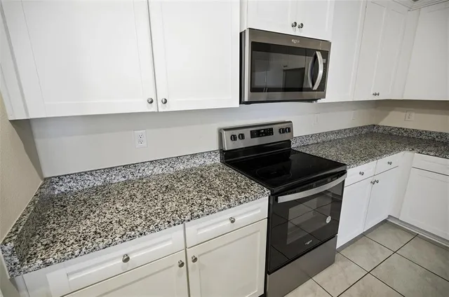a kitchen with granite countertop white cabinets and stainless steel appliances