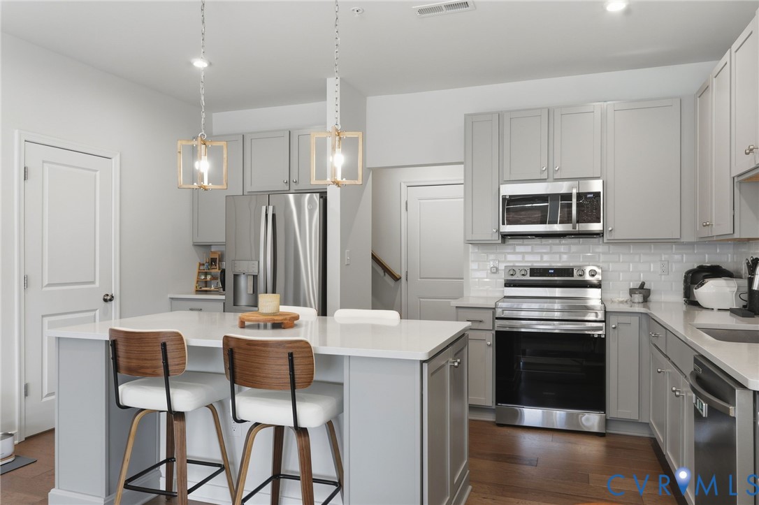 1900 Roseneath Road, Unit 4B Richmond, VA 23230 - Photo 9 of 44 a kitchen with stainless steel appliances kitchen island granite countertop a stove top oven a sink a refrigerator with a dining table and chairs