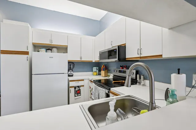 a kitchen with stainless steel appliances a stove a sink a refrigerator a microwave and cabinets
