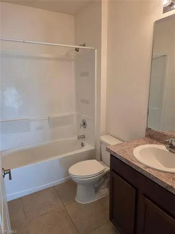 a bathroom with a granite countertop bathtub shower sink mirror vanity and toilet