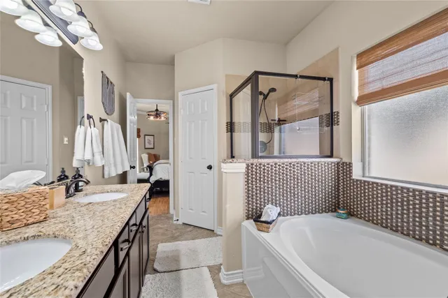 a bathroom with a granite countertop tub sink a mirror and shower