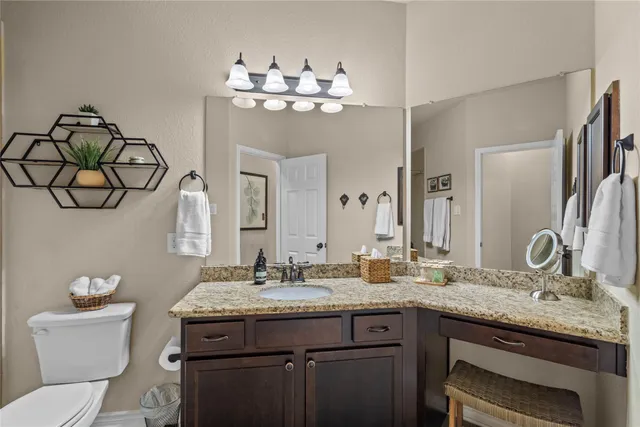a bathroom with a granite countertop sink a toilet and a mirror