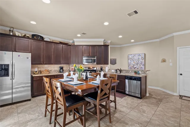 a kitchen with stainless steel appliances a table a sink a refrigerator and a refrigerator