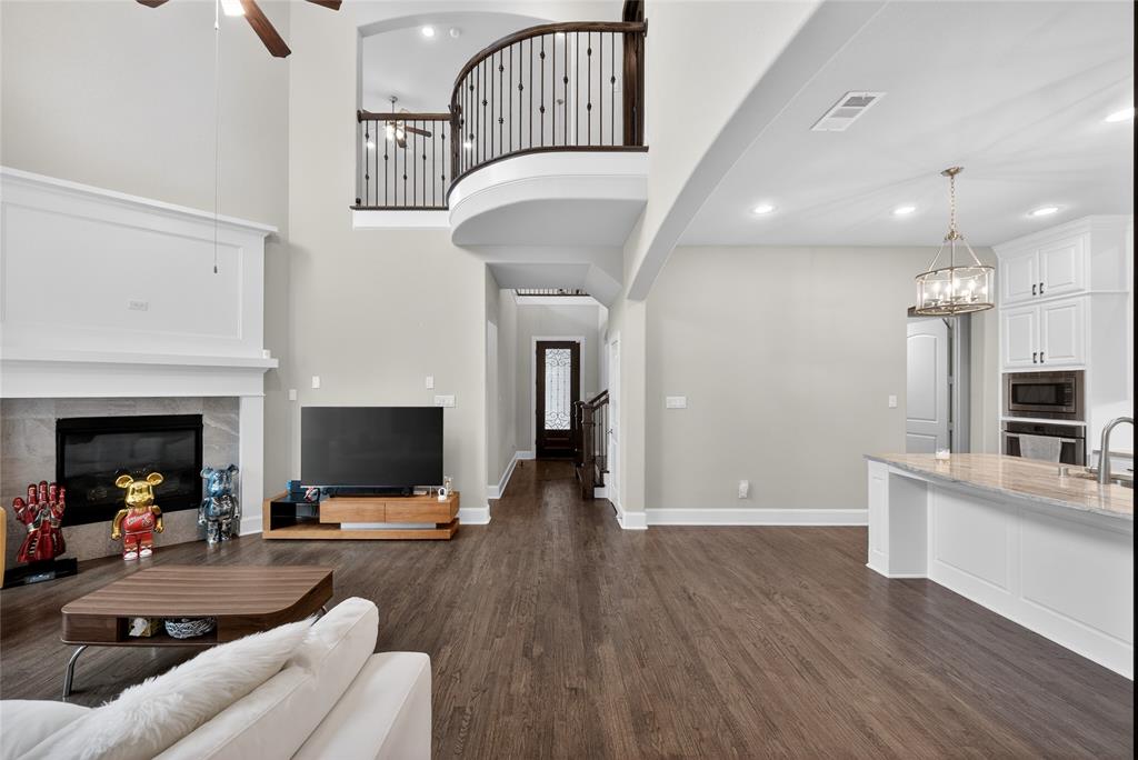 1039 Stephen Street Allen, TX 75013 - Photo 9 of 40 Living area with a premium fireplace, ceiling fan, dark wood-style floors, a high ceiling, and hanging lights