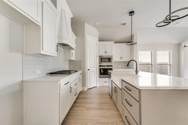 a kitchen with stainless steel appliances granite countertop a sink a stove and a wooden floors