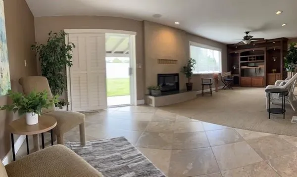a living room with furniture a fireplace a potted plant and a large window