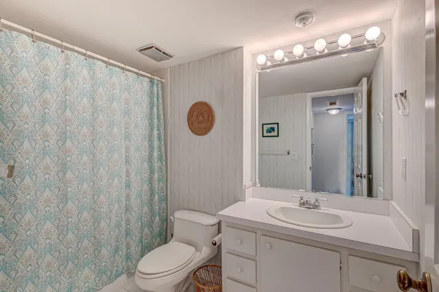 a bathroom with a toilet a sink a mirror a vanity and shower