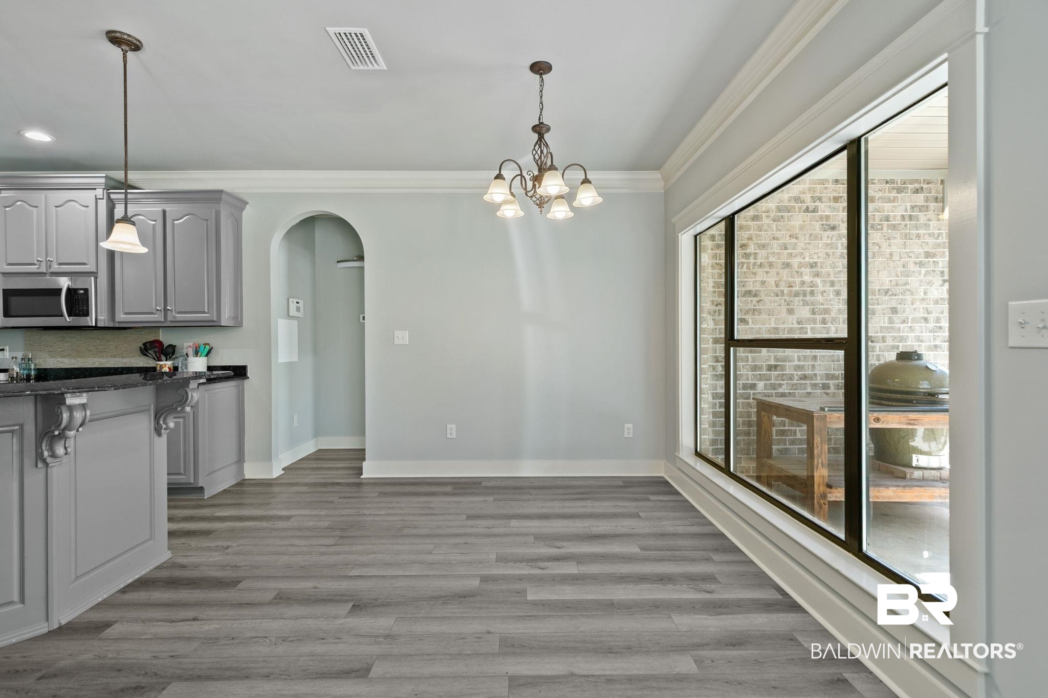 9584 Sanibel Loop Daphne, AL 36526 - Photo 13 of 48 Unfurnished dining area featuring arched walkways, hanging lights, light wood-type flooring, and ornamental molding