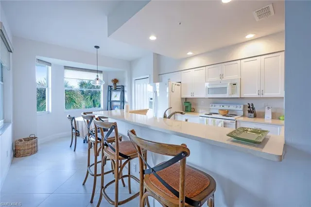 a kitchen with stainless steel appliances granite countertop table chairs sink and cabinets