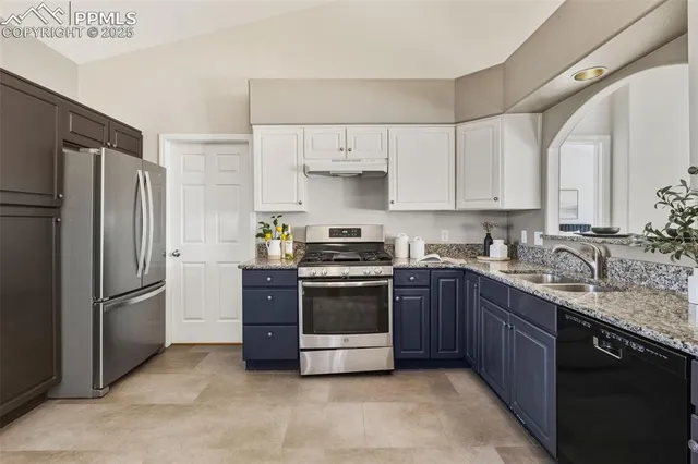 a kitchen with stainless steel appliances granite countertop a stove a refrigerator and a sink with wooden cabinets