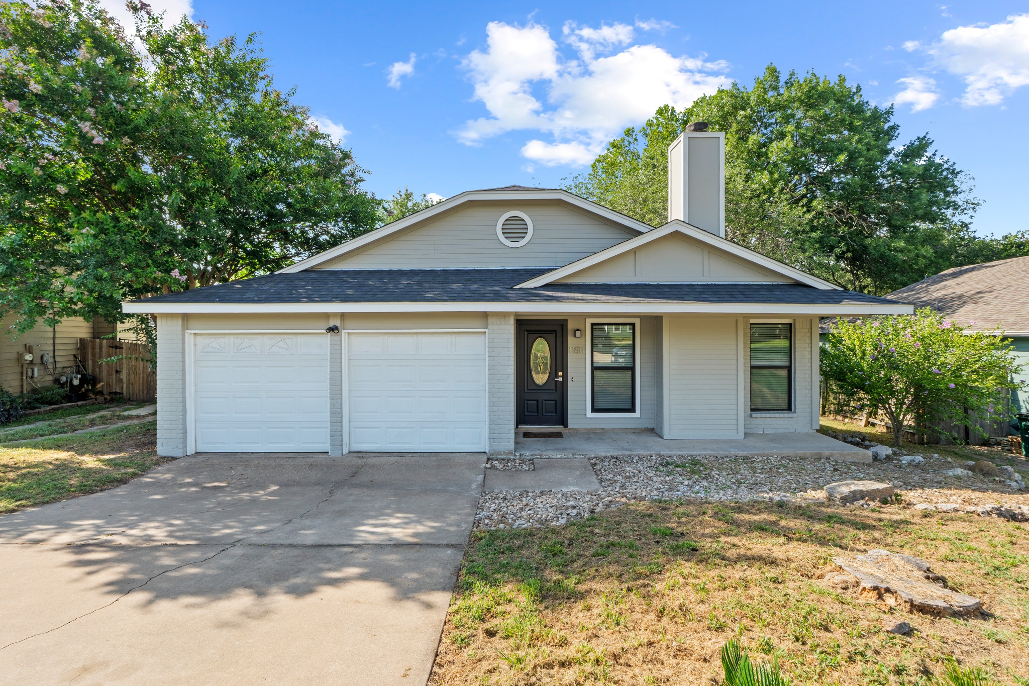 11811 Rotherham Drive Austin, TX 78754 - Photo 1 of 37 A welcoming facade with a classic gray exterior and dual garages, framed by mature trees.