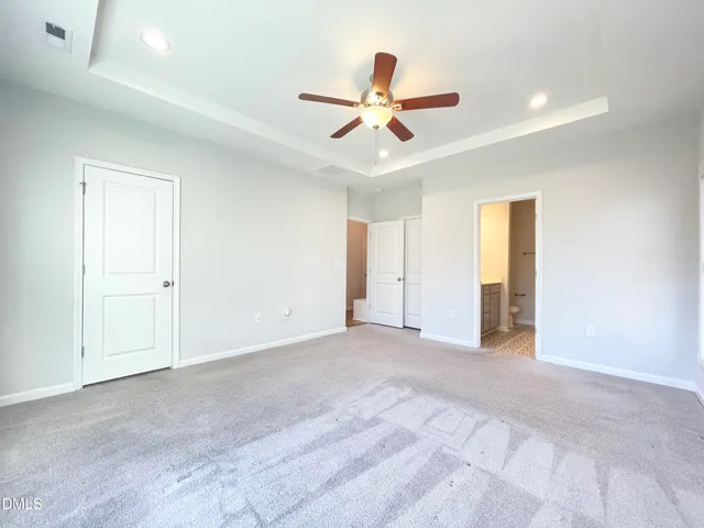 a view of an empty room and chandelier fan