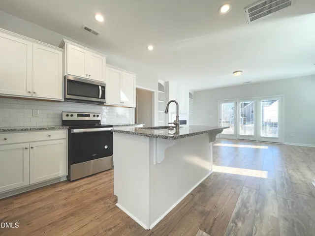 a kitchen with stainless steel appliances granite countertop a stove a sink and a microwave