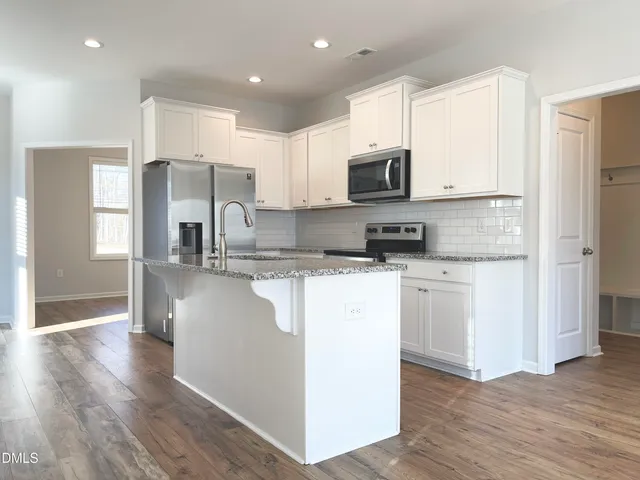 a kitchen with stainless steel appliances granite countertop a refrigerator sink and white cabinets