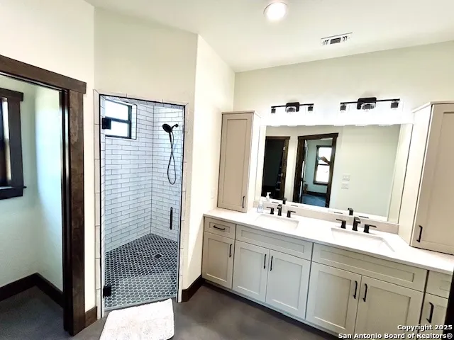 a spacious bathroom with a double vanity sink mirror and shower