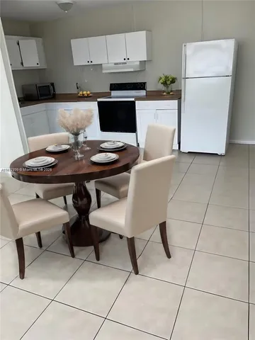 a kitchen with a table chairs and a refrigerator