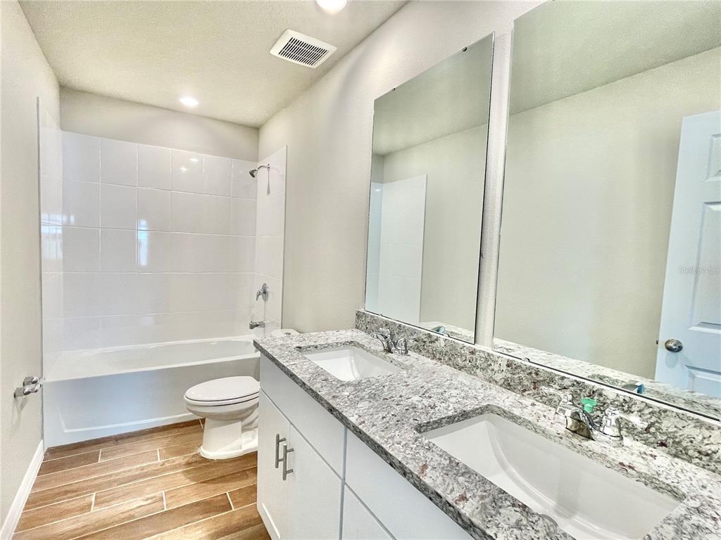 5232 Stephs Field Street St. Cloud, FL 34771 - Photo 33 of 43 a bathroom with a granite countertop sink toilet and shower