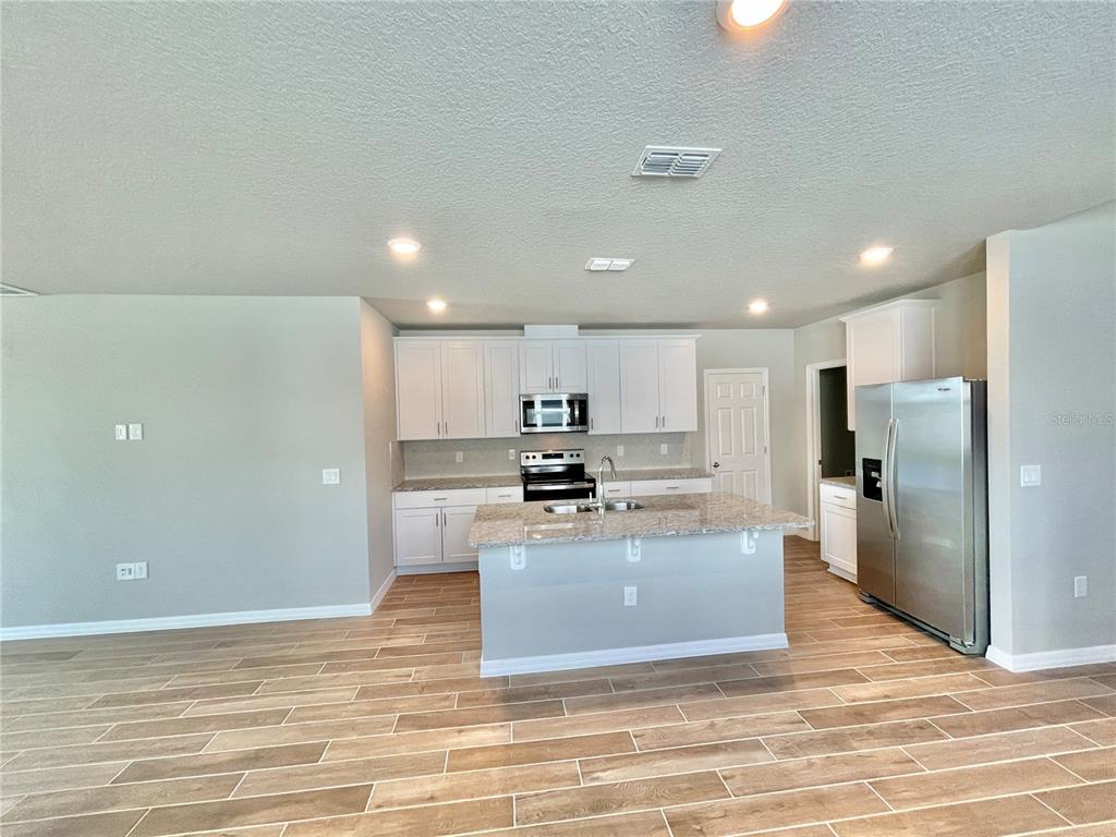 5232 Stephs Field Street St. Cloud, FL 34771 - Photo 10 of 43 a large kitchen with kitchen island a stove a refrigerator and a sink