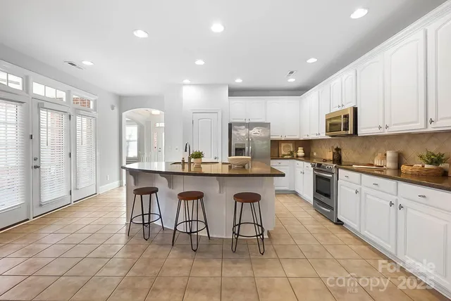 a kitchen with stainless steel appliances granite countertop a stove a sink a dining table and chairs