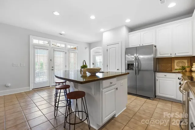 a kitchen with stainless steel appliances kitchen island granite countertop a refrigerator and cabinets