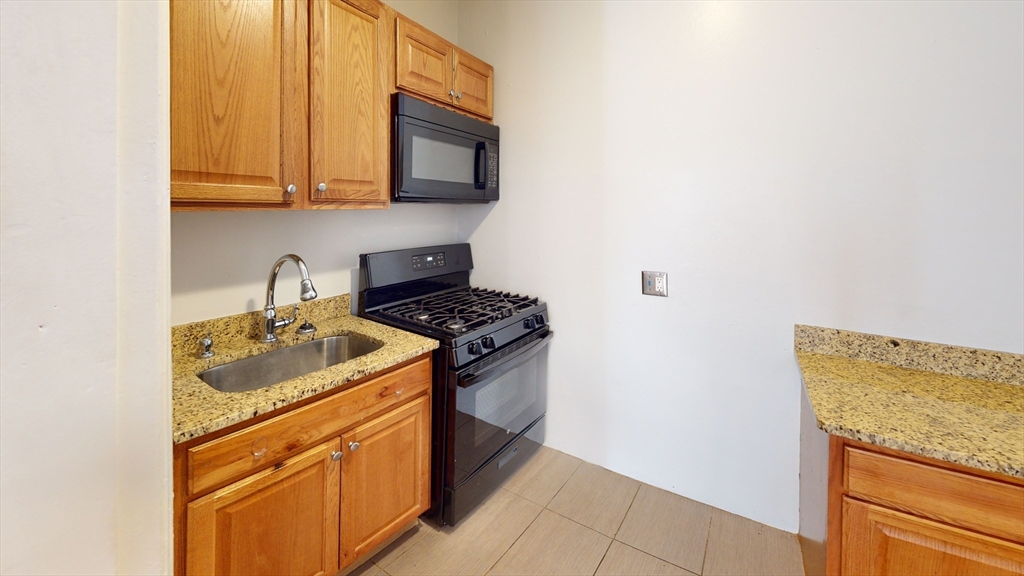 2999 Washington Street, Unit 1 Boston, MA 02119 - Photo 2 of 18 a kitchen with stainless steel appliances granite countertop a sink stove and microwave