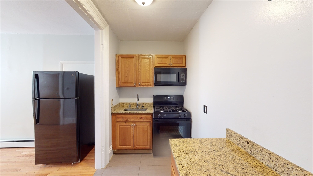 2999 Washington Street, Unit 1 Boston, MA 02119 - Photo 3 of 18 a kitchen with stainless steel appliances a refrigerator and a stove top oven